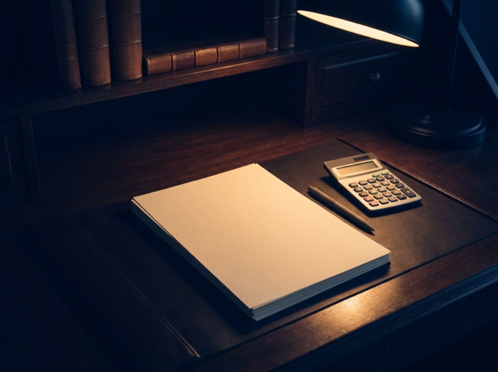 A desk with analysis sheets and a calculator under a warm lamp